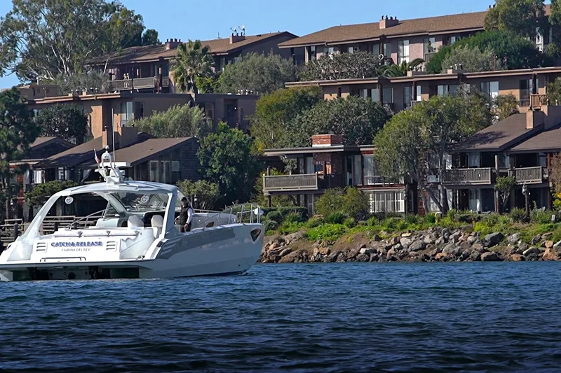Slide: The Image of 2017 Tritons Express cruiser on water near residential buildings and lush greenery. - 7