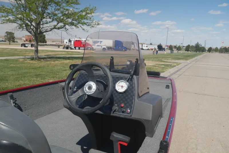 Slide: The Image of 2022 Tracker Bass Tracker Classic XL boat dashboard with steering wheel and gauge, parked outdoors. - 4