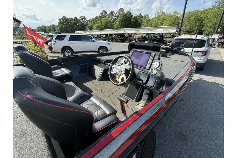 Slide: The Image of 2023 Nitro Z21 XL Pro boat interior with steering console and seating, parked outdoors. - 2