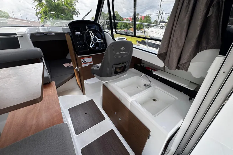 Slide: The Image of 2019 Jeanneau NC 795 boat interior with helm, seating, and dual sinks. - 10