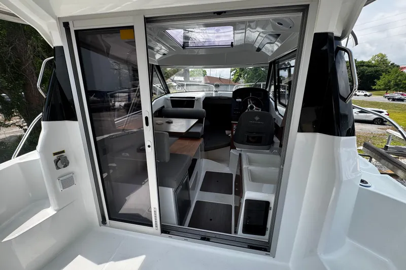 Slide: The Image of 2019 Jeanneau NC 795 boat interior with helm, seating, and sliding door. - 11