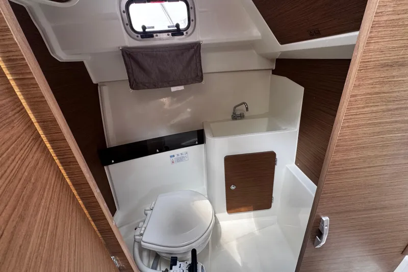 Slide: The Image of 2019 Jeanneau NC 795 boat bathroom with toilet, sink, and wooden accents. - 17