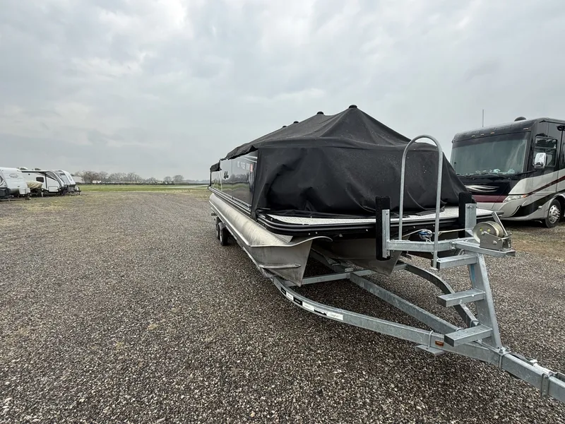 Slide: The Image of 2023 Avalon 2385 LSZ pontoon boat on trailer, covered, in gravel lot. - 3