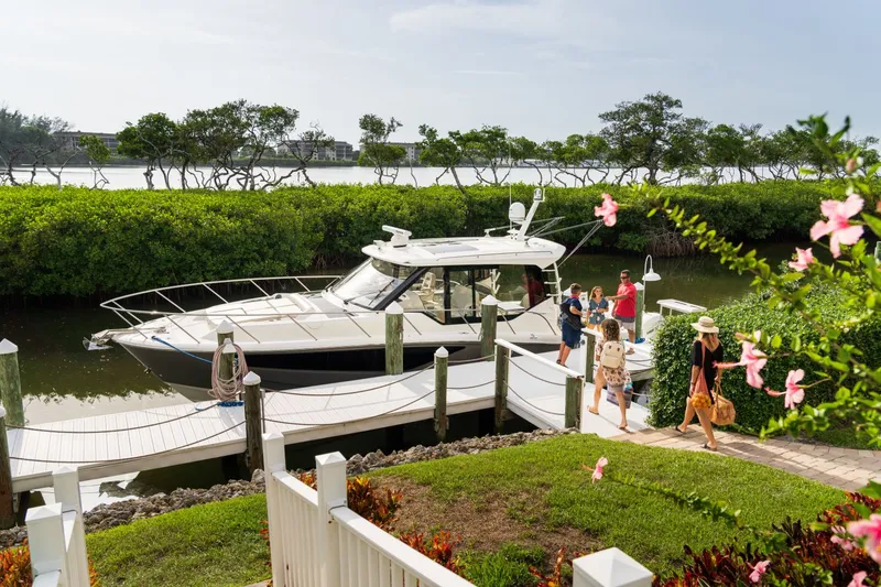 Slide: The Image of A Boston Whaler 405 Conquest is docked in a serene setting, surrounded by lush greenery and flowers. - 37