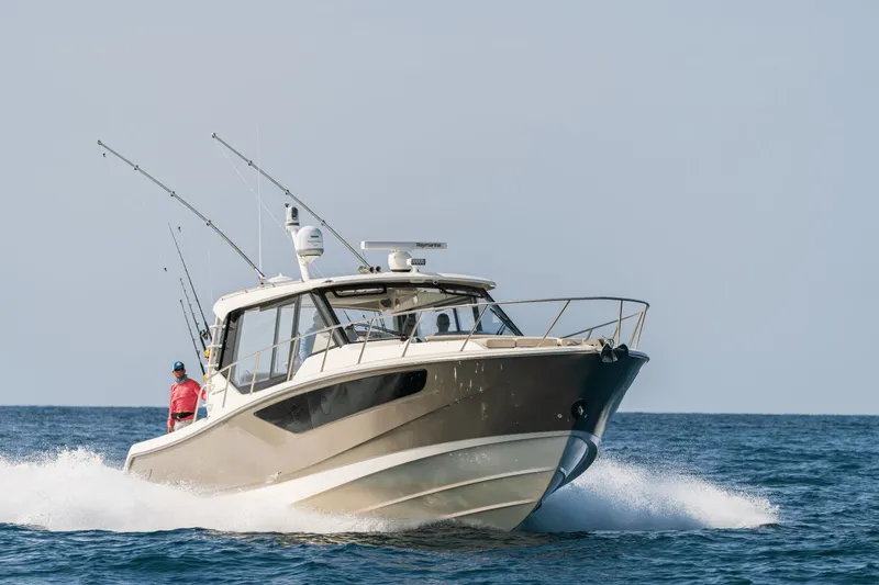 Slide: The Image of A 2026 Boston Whaler 405 Conquest speeds across the water, with fishing rods on board. - 28
