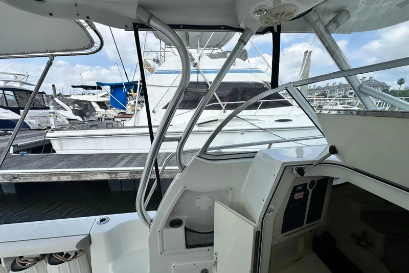 Slide: The Image of 2007 Polar 2700 Walkaround boat interior at marina, showcasing helm and docked vessels. - 25