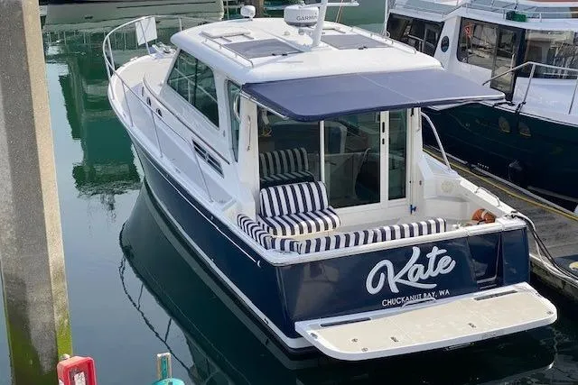Slide: The Image of 2013 Back Cove 34 boat docked, featuring a navy hull and striped seating. - 1