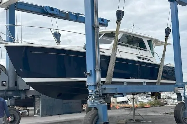 Slide: The Image of 2013 Back Cove 34 boat in dry dock, blue hull, white cabin, on a lift. - 24