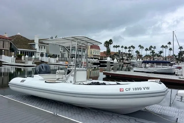 The Image of 2023 Novurania Como 18 boat docked in a marina with overcast skies. - 1