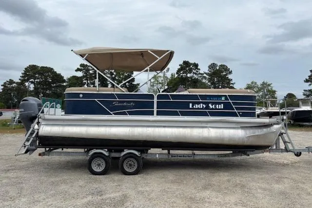 Slide: The Image of 2019 Sweetwater 2286 pontoon boat on trailer, featuring canopy and outboard motor. - 2