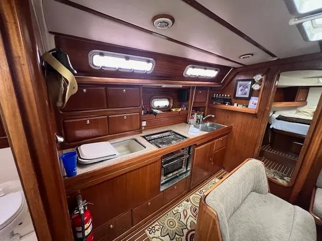 Slide: The Image of Interior of 2000 Bavaria 42 Cruiser yacht with wooden cabinetry and compact kitchen area. - 25