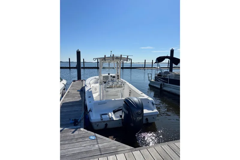 Slide: The Image of 2014 Sportsman Heritage 211 Center Console boat docked at marina under clear blue sky. - 3