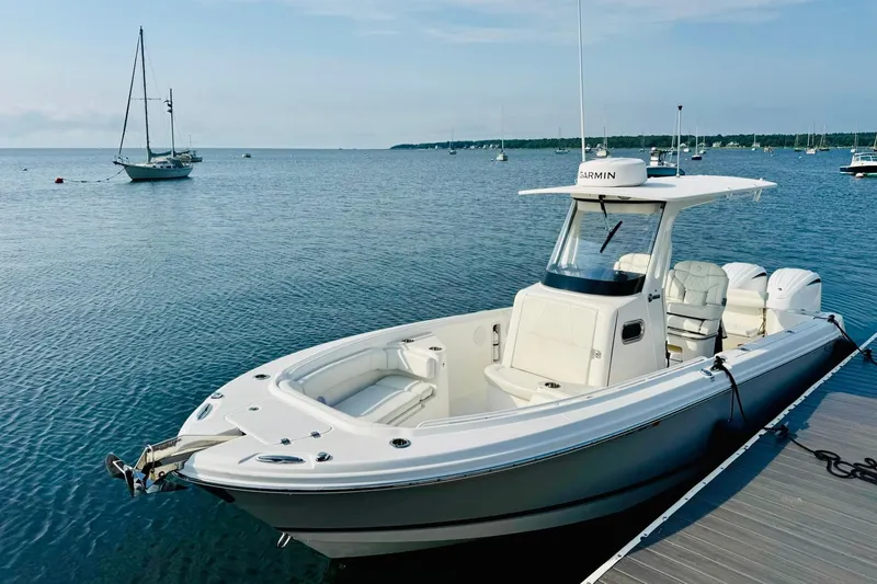 The Image of 2022 Edgewater 262CC boat docked on calm water with sailboats in the background. - 0