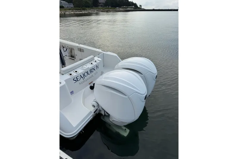 Slide: The Image of 2022 Edgewater 262CC boat with dual outboard motors, docked in calm waters. - 15