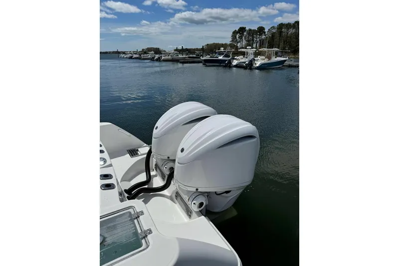 Slide: The Image of 2022 Edgewater 262CC boat with dual outboard motors docked in a marina. - 18
