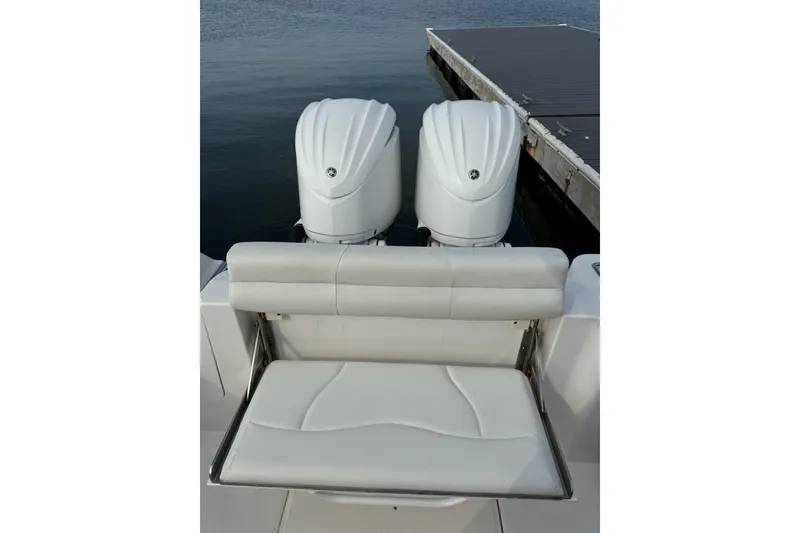 Slide: The Image of 2022 Edgewater 262CC boat with dual outboard engines and cushioned seating at the dock. - 21