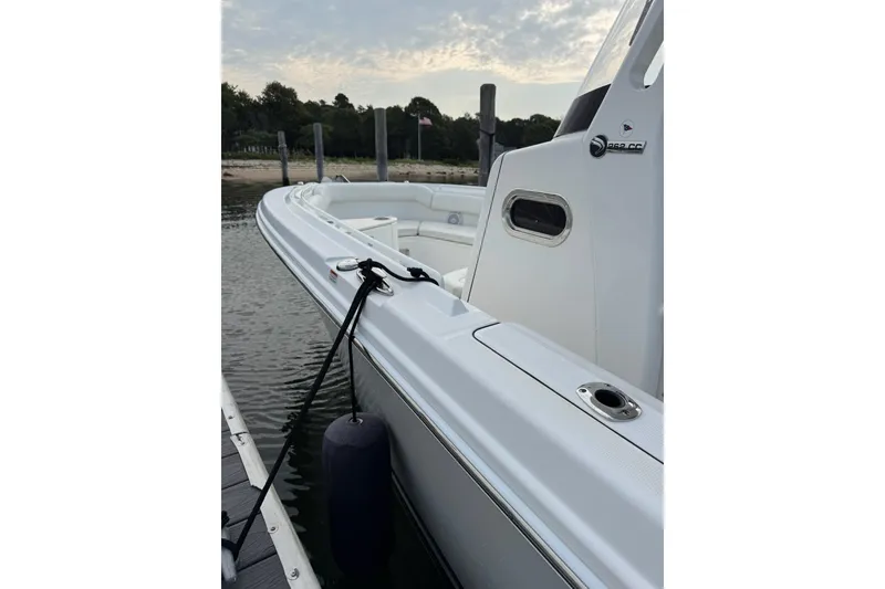 Slide: The Image of 2022 Edgewater 262CC boat docked, side view with calm water and shoreline background. - 28