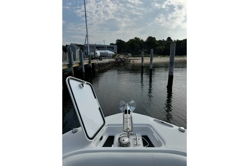 Slide: The Image of Bow view of 2022 Edgewater 262CC boat docked near a serene waterfront. - 29