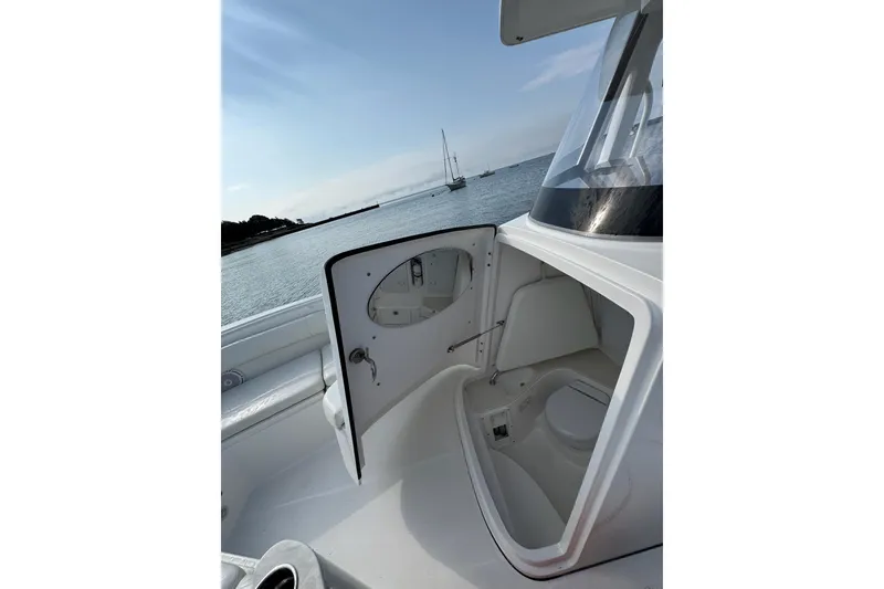 Slide: The Image of 2022 Edgewater 262CC boat interior with open storage compartment, ocean view in background. - 31