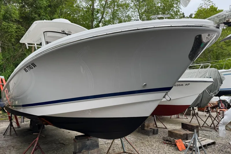 Slide: The Image of 2022 Edgewater 262CC boat on stands, surrounded by trees and other boats. - 5