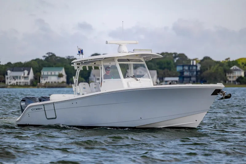 Slide: The Image of 2020 Cobia 350 Center Console boat cruising on a scenic waterway. - 2
