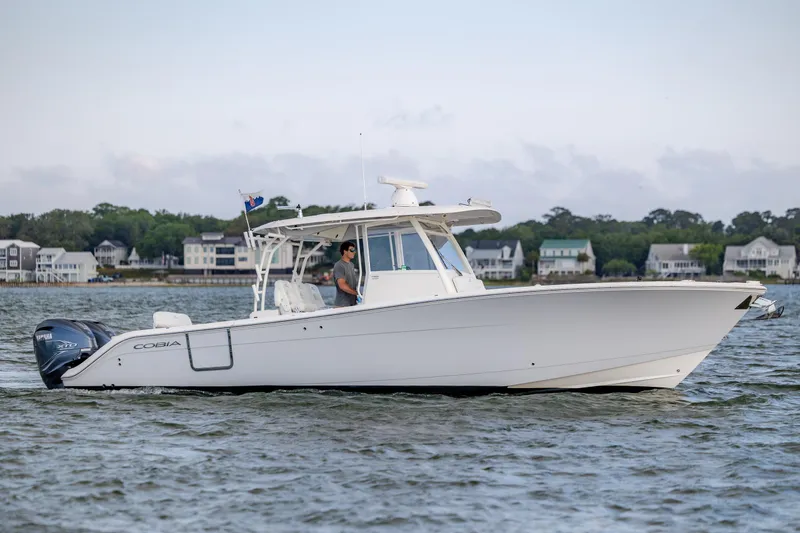 Slide: The Image of 2020 Cobia 350 Center Console boat cruising on a calm waterway near residential shoreline. - 3