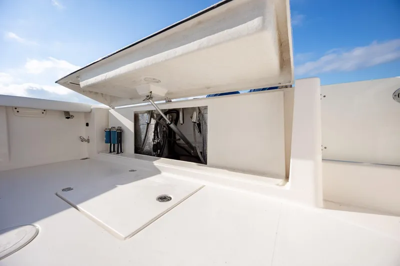 Slide: The Image of 2020 Cobia 350 Center Console boat storage compartment with open hatch under blue sky. - 36