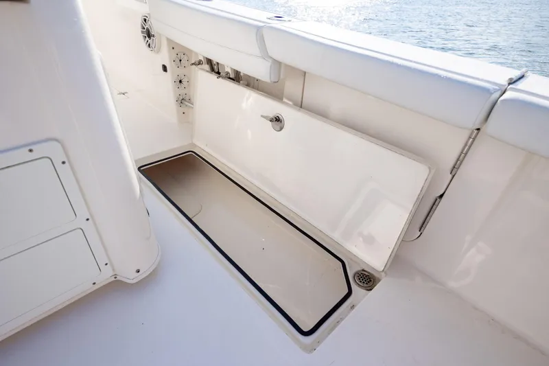 Slide: The Image of 2020 Cobia 350 Center Console boat storage compartment open by the water. - 38