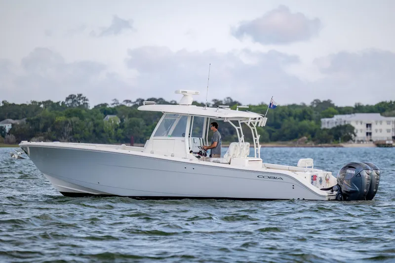 Slide: The Image of 2020 Cobia 350 Center Console boat cruising on a scenic waterway. - 7