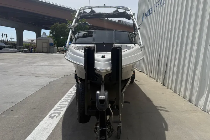 Slide: The Image of 2006 MB SPORTS B52 boat on trailer, parked near industrial area under bridge. - 2