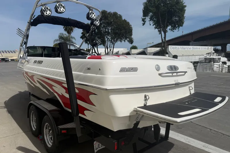 Slide: The Image of 2006 MB SPORTS B52 boat with red graphics on a trailer, parked near a marina. - 4