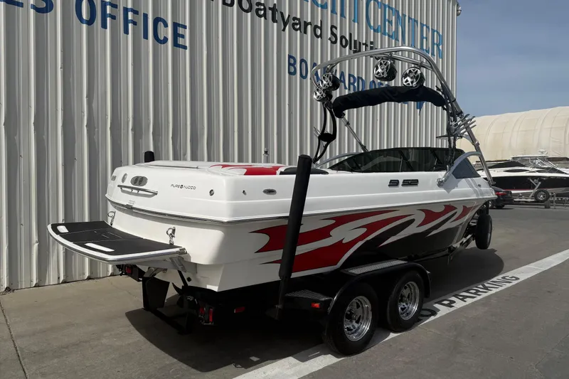 Slide: The Image of 2006 MB SPORTS B52 boat with red graphics, parked outside a sales office. - 6