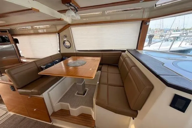 Slide: The Image of Interior of 2022 Ranger Tugs R-43 CB with brown leather seating and wooden table. - 8