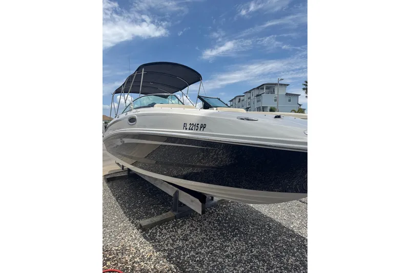 Slide: The Image of 2013 Sea Ray 280 Sundeck boat with canopy, parked on gravel under a clear sky. - 23