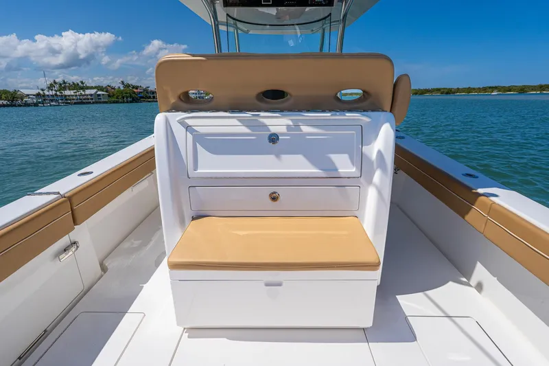 Slide: The Image of 2022 Valhalla Boatworks V-33 interior with tan seating and storage, on calm water. - 11