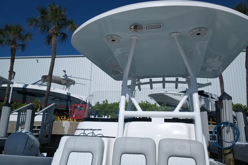 Slide: The Image of 2020 Sea Fox 249 Avenger boat docked, featuring T-top and seating, with palm trees in background. - 12
