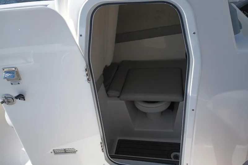 Slide: The Image of 2020 Sea Fox 249 Avenger boat interior with open door revealing compact toilet area. - 13
