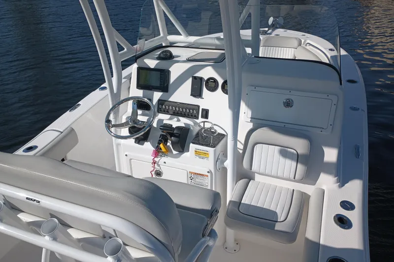 Slide: The Image of 2020 Sea Fox 249 Avenger boat cockpit with steering wheel and seating, on calm water. - 22