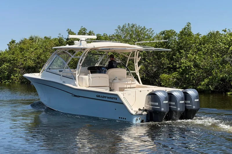 Slide: The Image of 2018 Grady-White Freedom 335 boat cruising on water with triple Yamaha engines. - 2