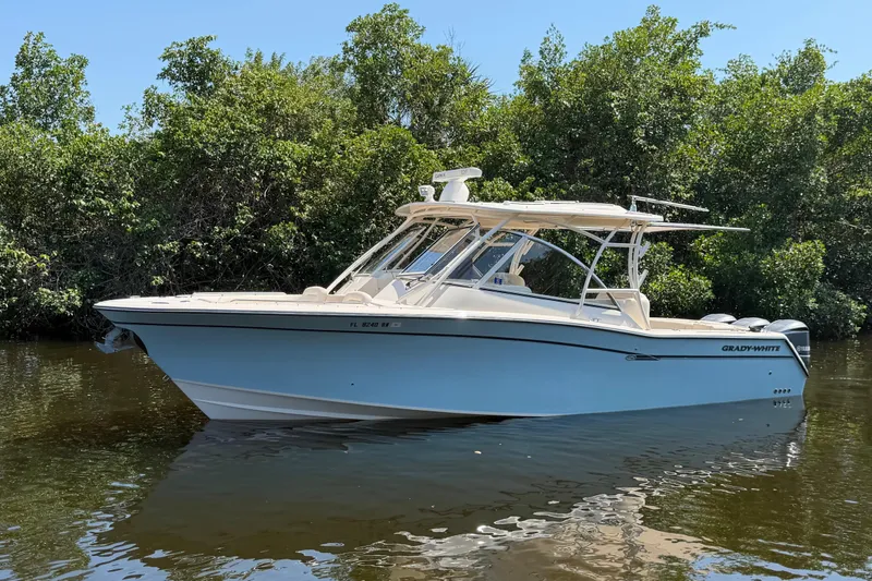 Slide: The Image of 2018 Grady-White Freedom 335 boat on calm water, surrounded by lush greenery. - 4