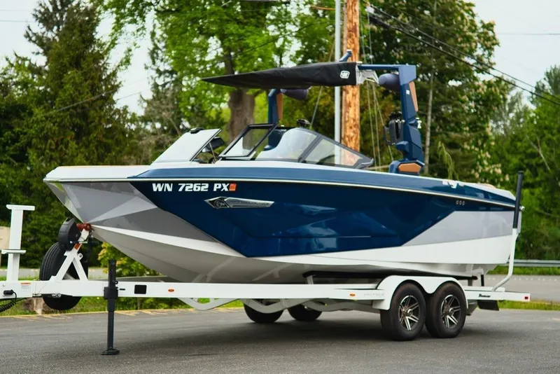 The Image of 2022 Nautique Super Air Nautique G23 on trailer, blue and white design. - 1