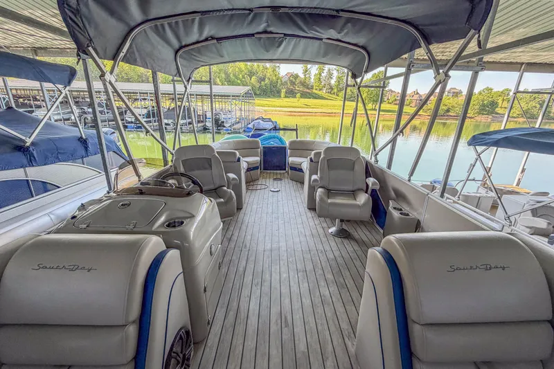 Slide: The Image of 2017 South Bay 523 RS pontoon boat interior with seating and canopy at a marina. - 7
