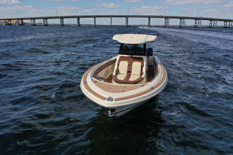Slide: The Image of 2021 Chris-Craft Catalina 34 boat cruising on open water near a bridge. - 1