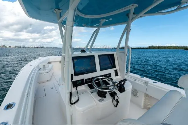 Slide: The Image of 2019 Contender 32 ST boat cockpit with dual screens, steering wheel, and ocean view. - 11