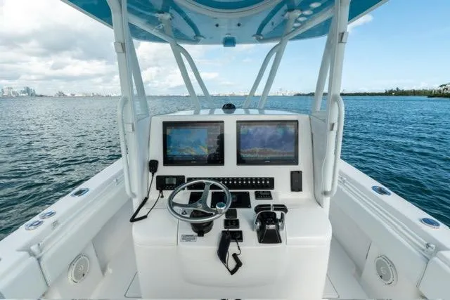 Slide: The Image of 2019 Contender 32 ST boat helm with dual screens, steering wheel, and ocean view. - 13