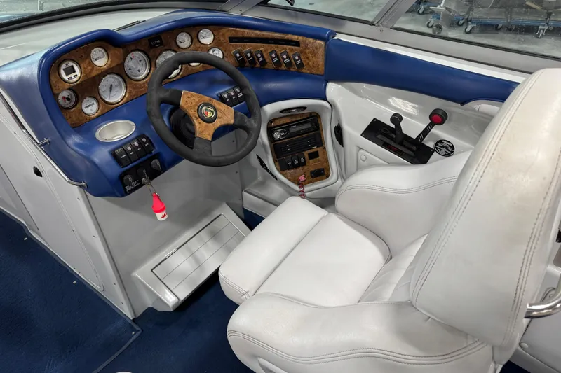 Slide: The Image of Interior of a 1998 Mariah 272 Shabah boat, featuring a detailed dashboard and white seating. - 13