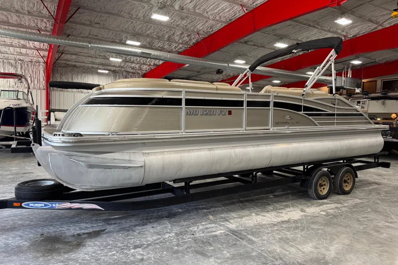 The Image of 2012 Bennington 25 QCW pontoon boat on trailer in indoor storage facility. - 1