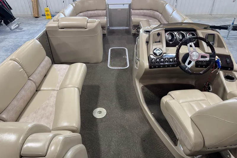 Slide: The Image of Interior of a 2012 Bennington 25 QCW boat with beige seating and modern dashboard. - 11