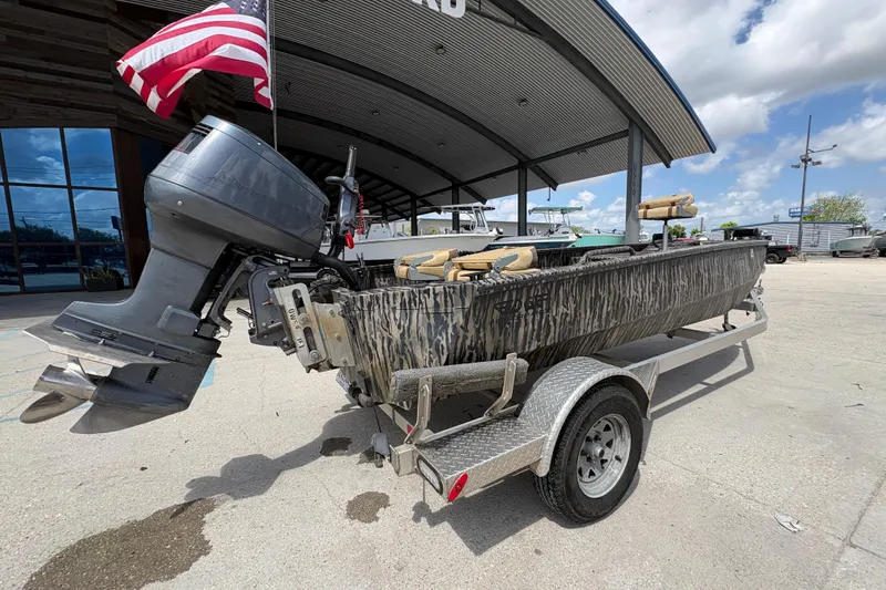 Slide: The Image of 2022 Edge Duck Boats HPSD 1656DB on trailer, camo design, American flag, outdoor display. - 3