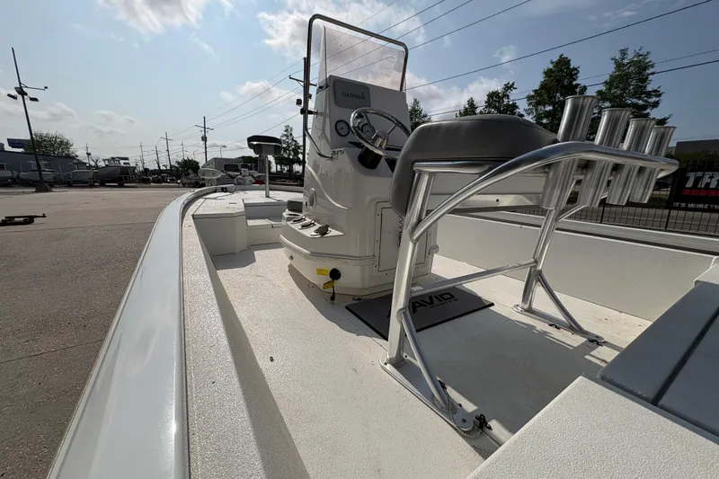 Slide: The Image of 2021 Avid 21 FS boat interior with steering console and rod holders under a sunny sky. - 15